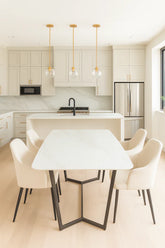 Modern kitchen with a dining table and chairs in a light color scheme.
