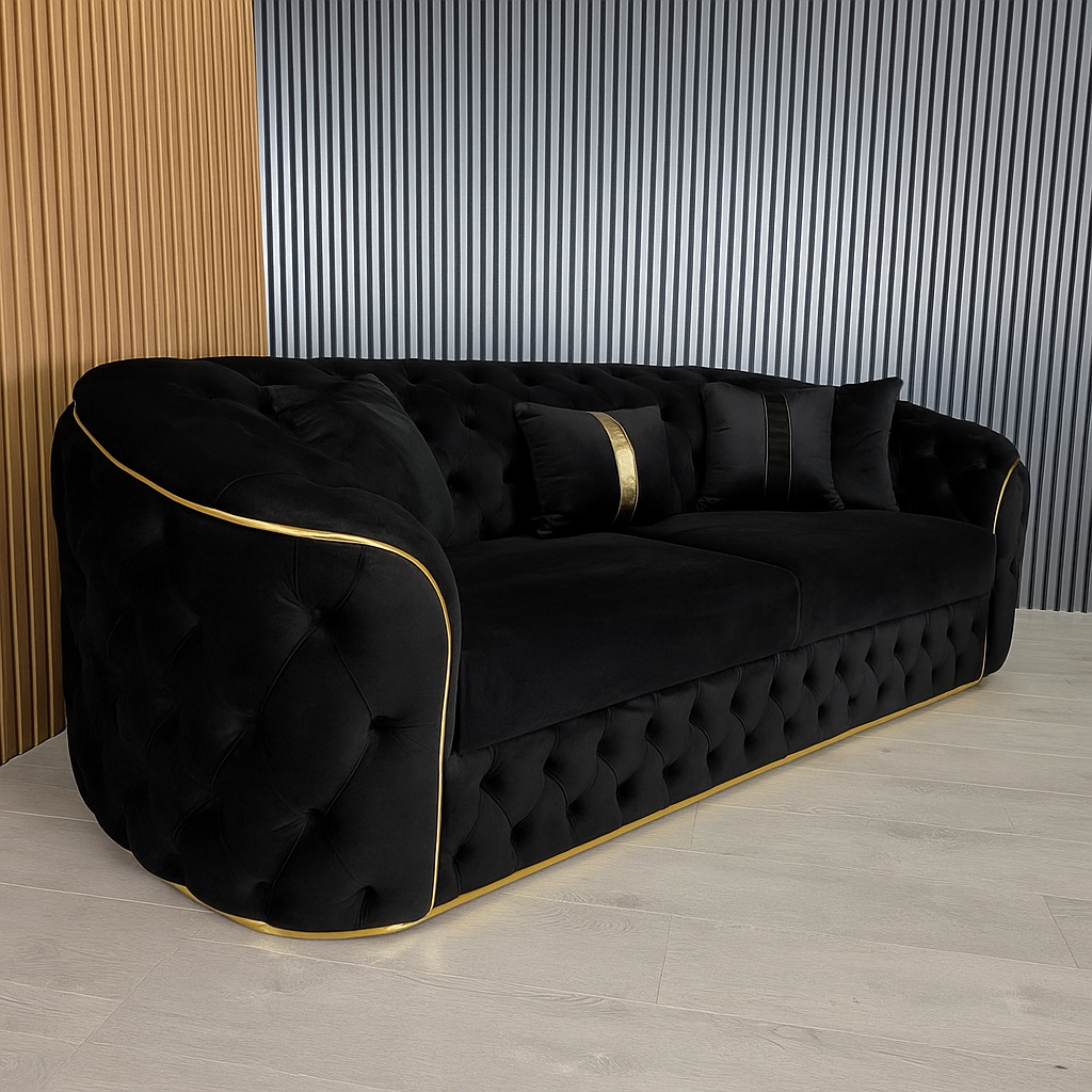 Black tufted sofa with gold trim against a striped wall.